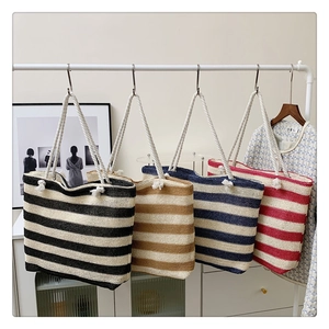Detail view of four striped woven tote bags in black, blue, and red with rope handles