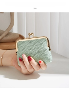 Close-up of mint green woven texture coin purse with golden clasp held in hand
