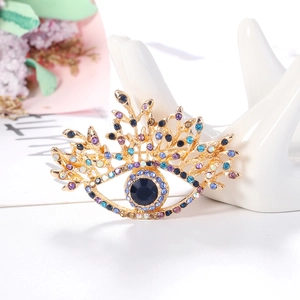 Retro vintage gold eye brooch with colorful rhinestones on a white surface