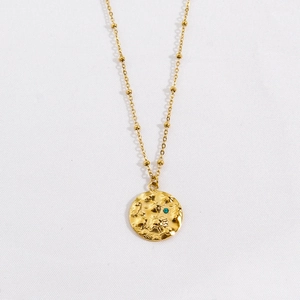 Close-up of golden sun-embossed pendant with turquoise stone on bead chain