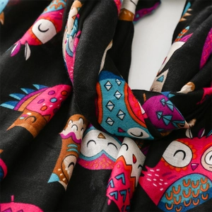 Close-up of cotton-linen blend fabric with colorful cartoon owl patterns on black scarf