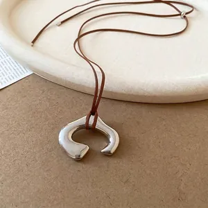 Minimalist irregular C-shaped silver pendant necklace with a stylish brown cord strap