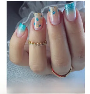 Detail of blue gradient press-on nails with gold foil petals and sparkling gold rings