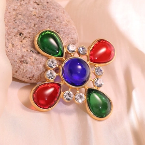 Detailed macro view of vintage cross brooch with colorful gemstones on silk