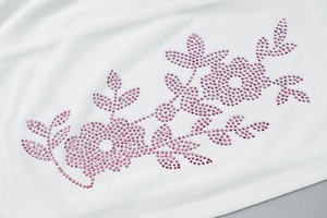 Detailed close-up of pink rhinestone floral pattern on high-quality white fabric