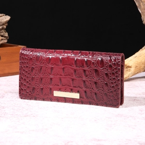 Detailed close-up of wine red crocodile pattern leather texture on a long wallet