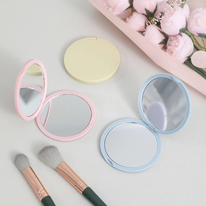 Portable folding compact makeup mirror in round pastel designs for daily vanity use