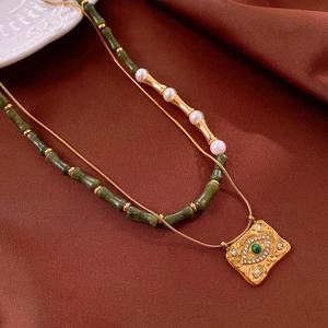 Détail du collier double couche avec pendentif carré œil protecteur et perles vertes