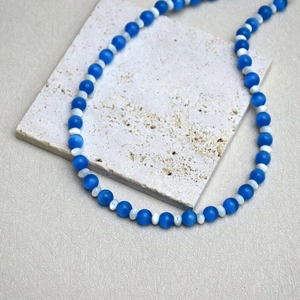 Detail of blue cat eye stone beads and heart pendant on a stone display base