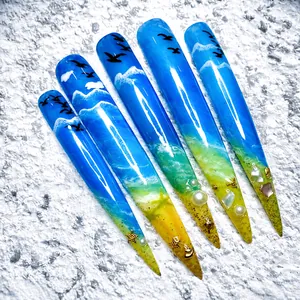 Detail of stiletto press-on nails with ocean theme, blue gradient, waves and pearl charms
