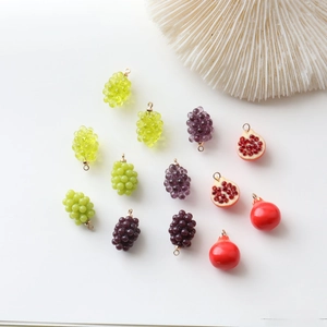 Detailed view of mini resin grape and pomegranate charms for DIY jewelry making