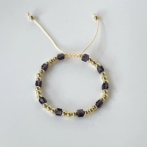 Detail of beaded bracelet with 18k gold plated metal beads and purple crystal cubes