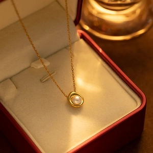 Macro shot of an elegant pearl pendant on a gold chain inside a luxury red jewelry box