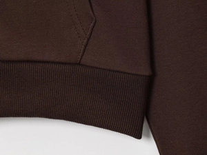 Macro detail of dark brown knit fabric with ribbed hem and stitching on a zip jacket