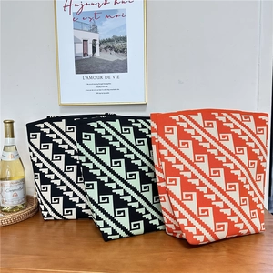 Three knitted tote bags with geometric zigzag patterns displayed on a wooden table