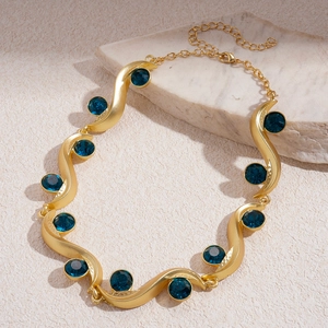 Detail of luxury gold wavy sweater chain with deep blue round crystals and lobster clasp