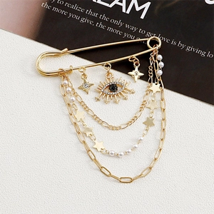 Detail of gold evil eye brooch featuring layered chains, star charms and rhinestones