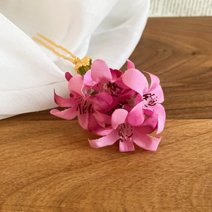 Détail de fleurs en tissu rose délicat sur une élégante épingle à cheveux dorée chic
