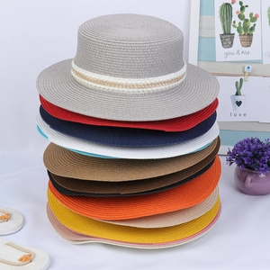 Macro detail of various colorful straw hats stacked with elegant pearl gold chain bands