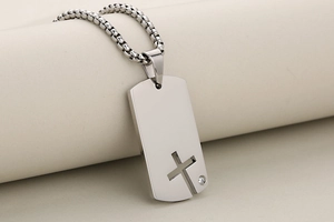 Vue macro d'un pendentif croix en acier inoxydable avec découpe laser et zircon