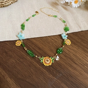 Detail of sunflower necklace with green beads and gold chain on rustic wooden surface