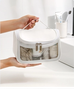 Detailed view of a white PVC cosmetic bag with a transparent window held by hands