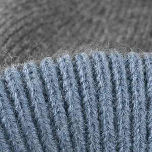 Close-up of greyish blue knit beanie featuring thick wool texture and ribbed pattern