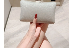 Close-up of elegant silver rhinestone evening clutch bag held by hand on marble background