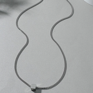 Minimalist cube pendant on stainless steel chain necklace with subtle leaf shadows