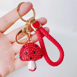 Detail of red resin mushroom keychain with sparkling rhinestones and woven wrist strap