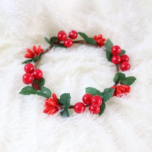 Macro shot of artificial Christmas candle ring with red berries and green leaves on fur