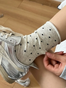 Gros plan sur des chaussettes beiges à pois noirs avec des baskets métalliques