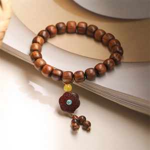 Macro shot of dark wood beads with a turquoise stone and carved floral charm