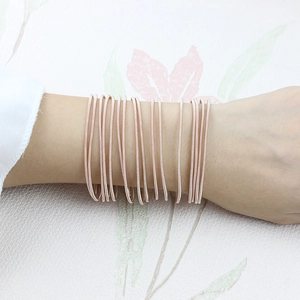 Detail of rose gold guitar string style multi-strand carbon steel wire bracelet on wrist