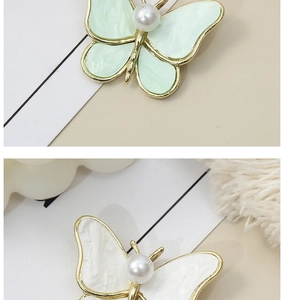 Detail showing elegant butterfly brooches with marble resin wings and central pearl inlay