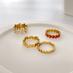 Detailed display of daisy enamel and red heart rings on a white ceramic plate