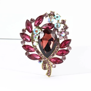 Close-up of floral brooch with burgundy teardrop gem and pink rhinestones on gold base