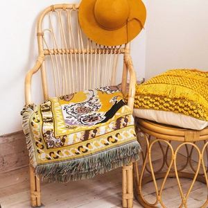 Close-up of yellow bohemian woven blanket with colorful tassels and nature-inspired patterns