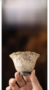 Close-up of hand-painted wisteria ceramic teacup with gold rim and stony texture finish