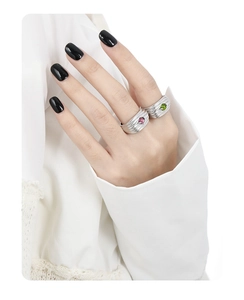 Detail of layered S925 silver textured rings with magenta and emerald stones