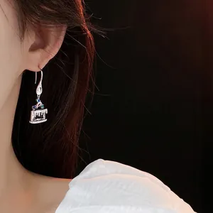 Creative cupcake drop earrings with colorful zircon stones worn by a model in profile
