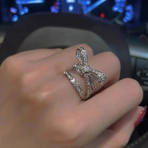 Close-up of a silver bow knot ring with sparkling crystals on a model's finger