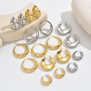 Polished hollow hoop earrings in gold and silver showing various sizes on geometric props