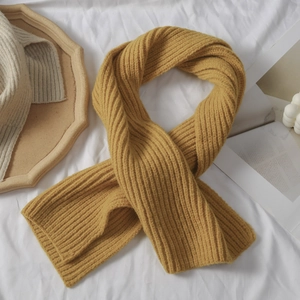 Nahaufnahme von grobem Rippstrickschal in Gelb und Beige auf einem Holztablett