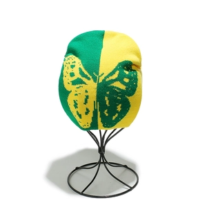 Détail du bonnet en maille papillon bicolore avec un design divisé vert et jaune vif