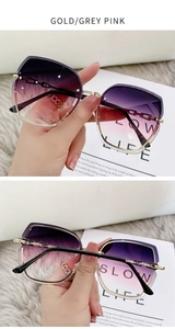 Detail view of gold rimless sunglasses with purple pink gradient lenses and crystal accents