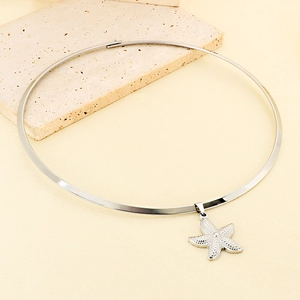 Macro shot of silver starfish pendant necklace with textured surface on a stone plate