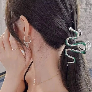 Silver snake hair claw clip with green accents worn on hair for a sleek look