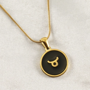 Close-up of 18K gold snake chain necklace with black enamel Taurus constellation pendant