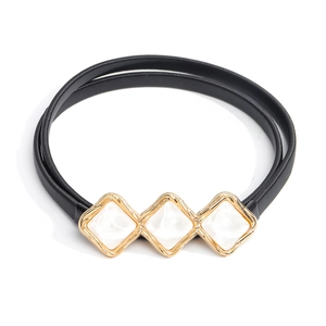 Detail of black elastic belt with gold metal trim and three white diamond buckle accents